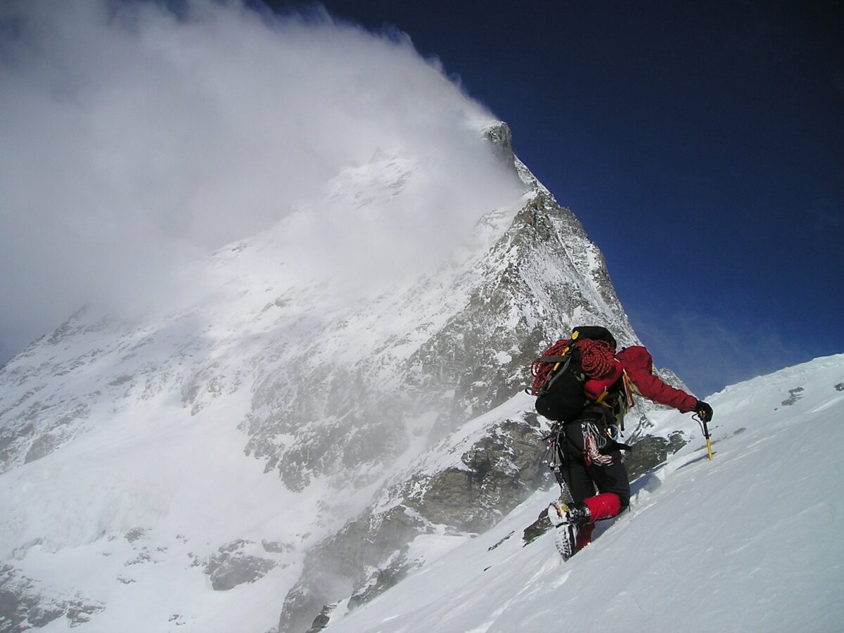 person climbing snow covered mountain